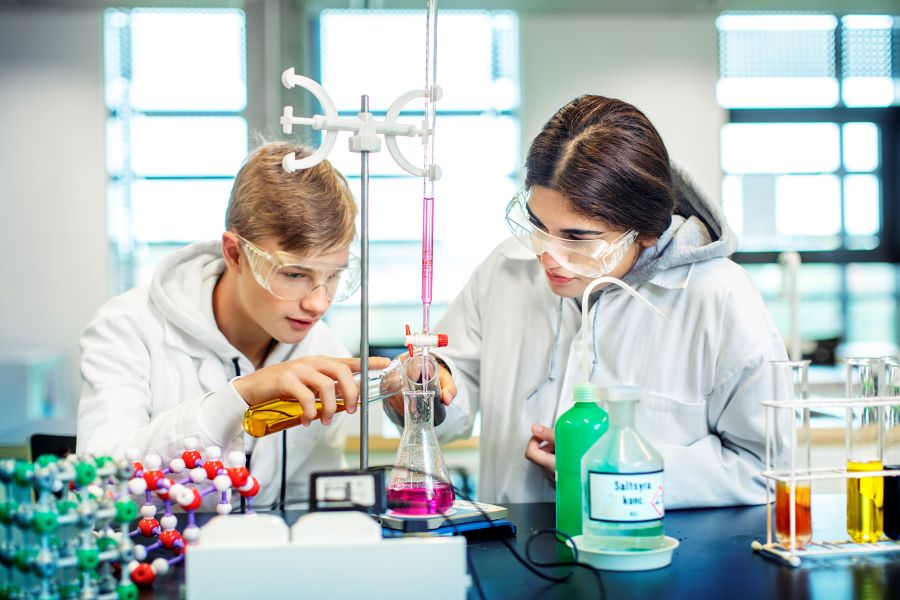 Två elever som håller på med en laboration i kemisal.