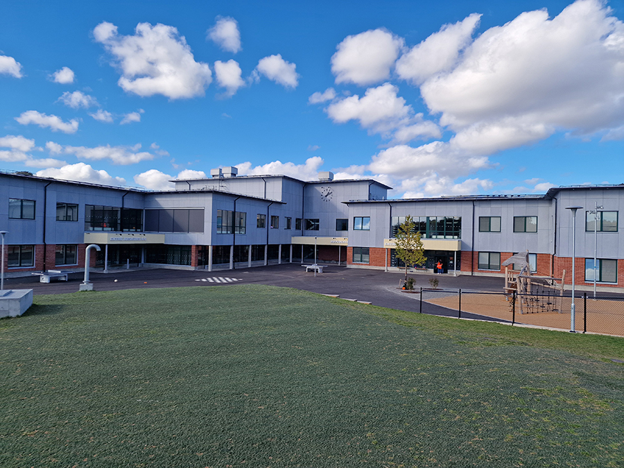 Bilden är tagen utomhus på baksidan av Viraskolan med utsikt över byggnaden och en del av skolgården.