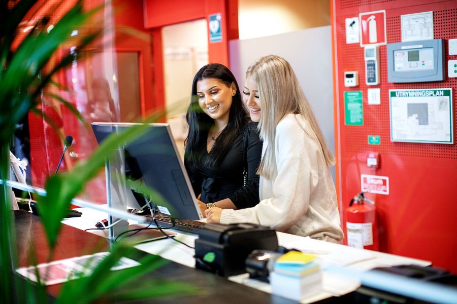 Två elever på hotell- och turismprogrammet i en reception