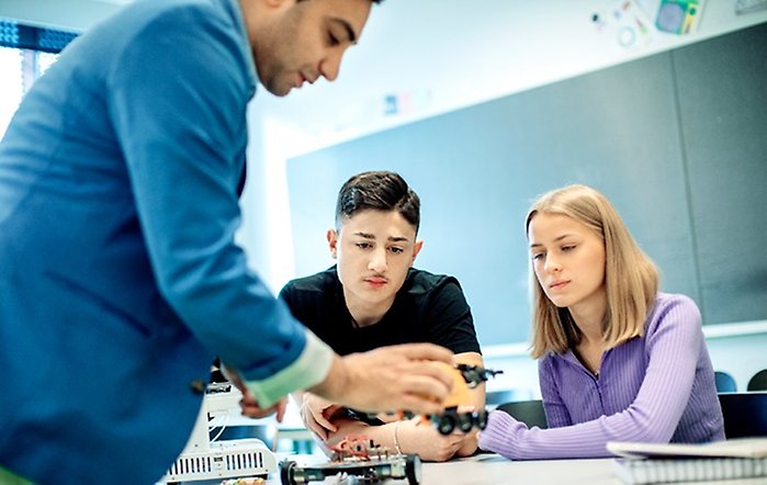 Två elever och en lärare i ett klassrum.