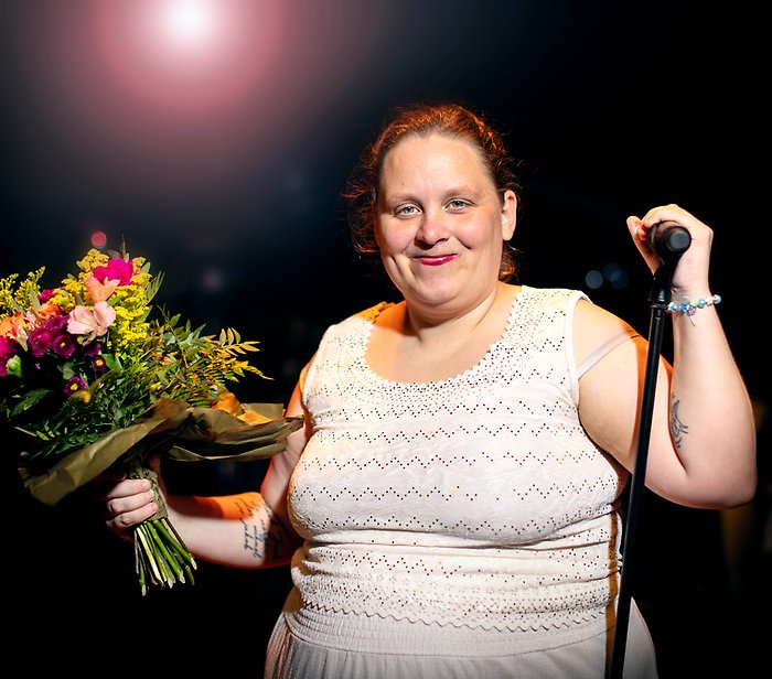 Bild på Nikki. Hon har en vit klänning på sig och ler.