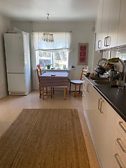 Kök med bord, stolar, kylskåp och diskbänk.