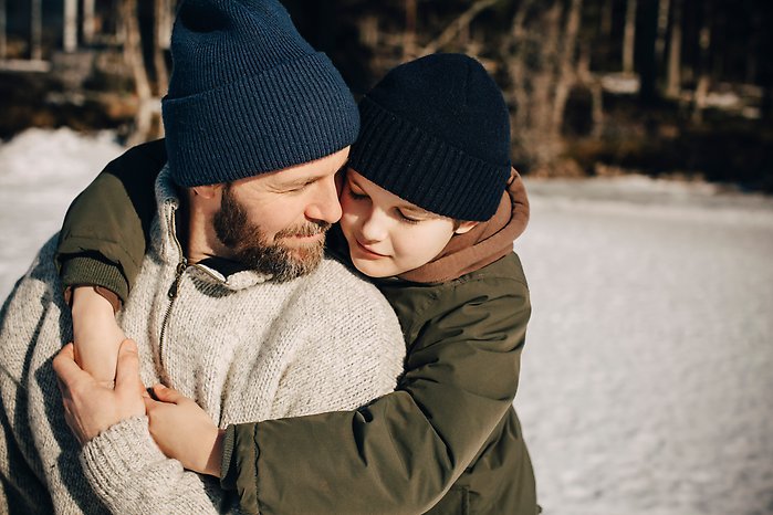pojke och pappa kramas i snön